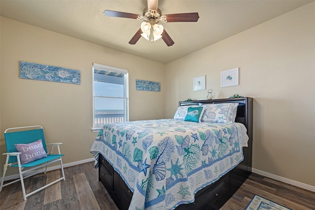 bedroom featuring a textured ceiling, dark wood-style flooring, a ceiling fan, and baseboards