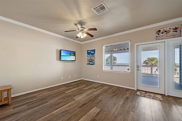 unfurnished room with visible vents, ornamental molding, a ceiling fan, wood finished floors, and baseboards