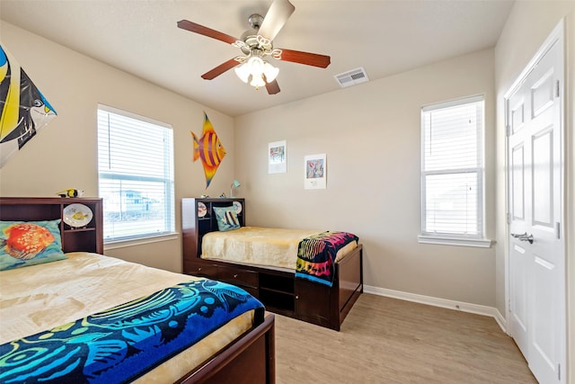 bedroom with light wood-type flooring, visible vents, ceiling fan, and baseboards