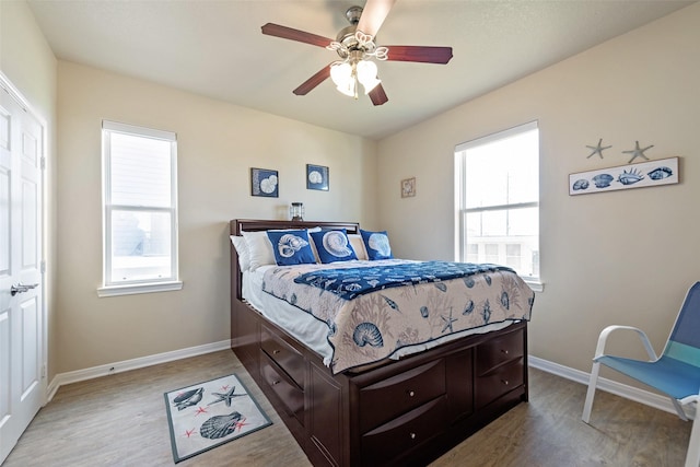 bedroom featuring multiple windows, baseboards, and wood finished floors