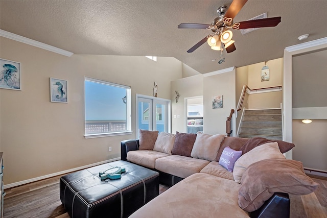 living area with ceiling fan, stairway, wood finished floors, vaulted ceiling, and a textured ceiling