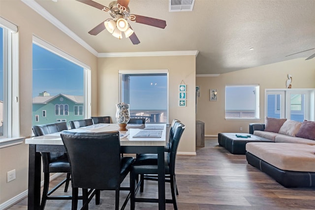 dining room with a wealth of natural light, visible vents, crown molding, and wood finished floors