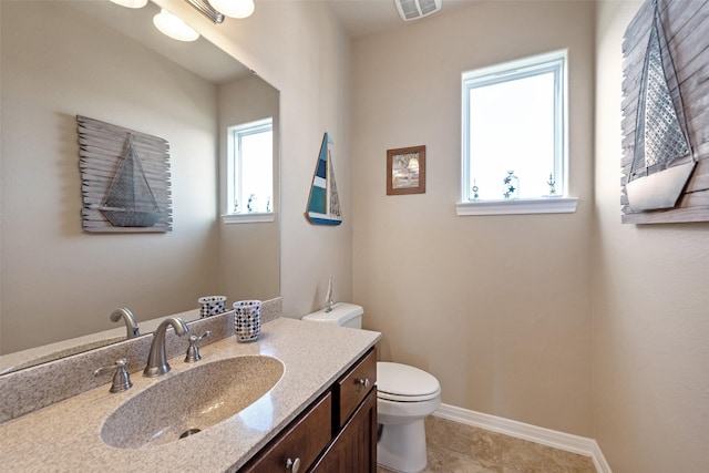 half bath featuring baseboards, visible vents, toilet, tile patterned flooring, and vanity