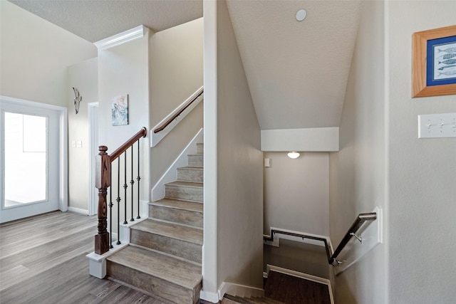 stairs featuring a textured ceiling, baseboards, and wood finished floors