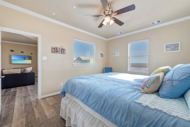 bedroom with ceiling fan, wood finished floors, visible vents, baseboards, and crown molding