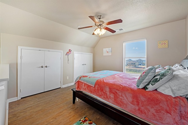 bedroom with a textured ceiling, visible vents, a ceiling fan, vaulted ceiling, and light wood-type flooring