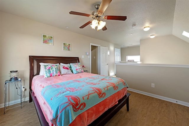 bedroom with ceiling fan, a textured ceiling, baseboards, and wood finished floors