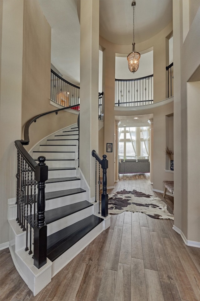 entryway featuring a notable chandelier, a high ceiling, baseboards, and wood finished floors