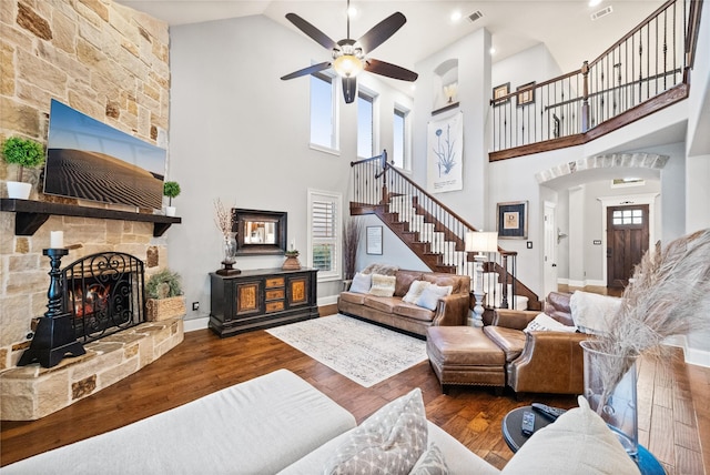 living area with stairs, visible vents, a fireplace, and wood finished floors