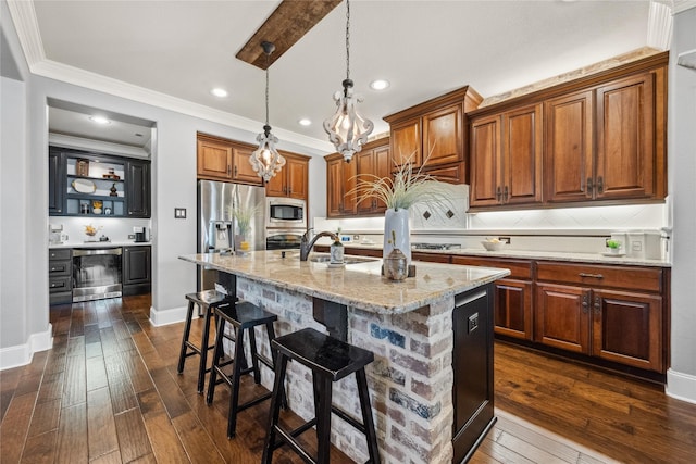 kitchen with brown cabinets, dark wood finished floors, appliances with stainless steel finishes, light stone countertops, and a kitchen breakfast bar