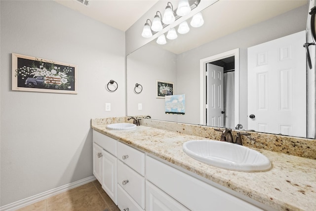 bathroom with double vanity, tile patterned flooring, baseboards, and a sink