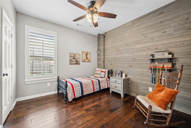 bedroom with ceiling fan, wooden walls, visible vents, and dark wood-style flooring