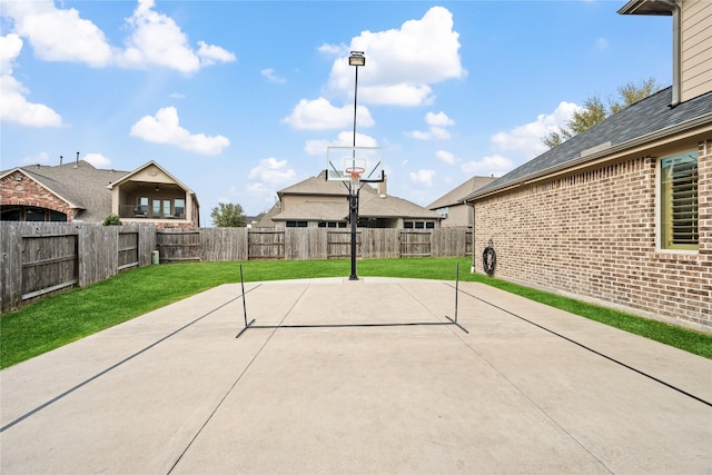 view of basketball court featuring a lawn and a fenced backyard