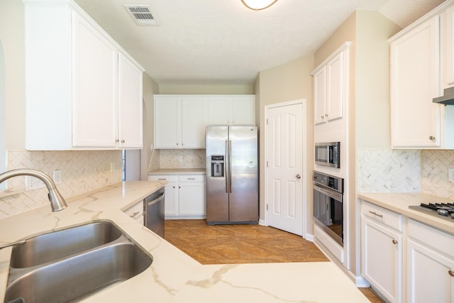 kitchen featuring a sink, visible vents, white cabinets, appliances with stainless steel finishes, and light stone countertops