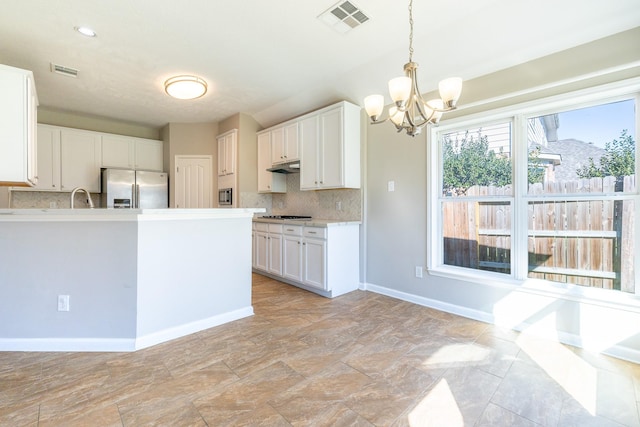 kitchen featuring stainless steel appliances, visible vents, under cabinet range hood, and decorative backsplash