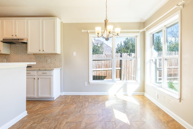 kitchen with tasteful backsplash, light countertops, plenty of natural light, and under cabinet range hood