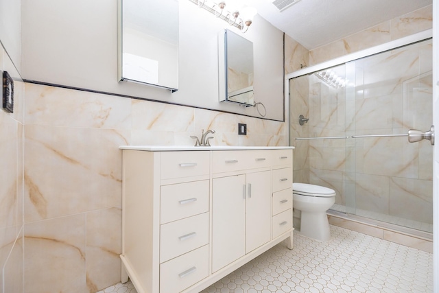 full bath with toilet, vanity, a shower stall, and tile walls