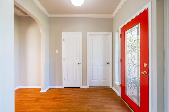 entryway featuring light wood-style flooring, arched walkways, baseboards, and ornamental molding