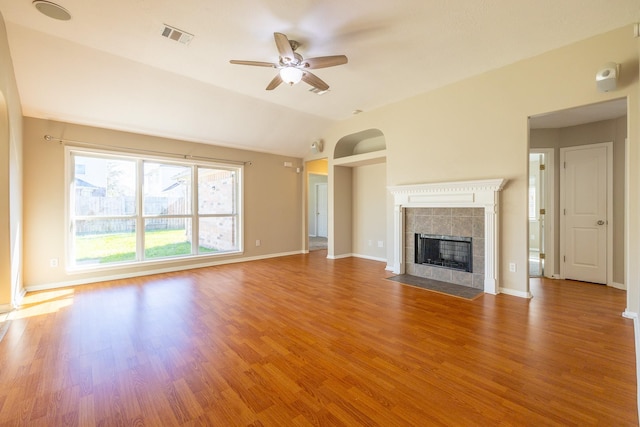 unfurnished living room with a tile fireplace, visible vents, baseboards, and wood finished floors