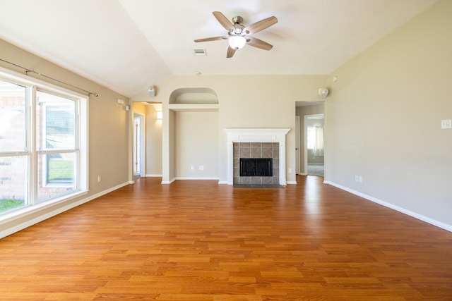 unfurnished living room with lofted ceiling, visible vents, light wood-style flooring, and a tiled fireplace