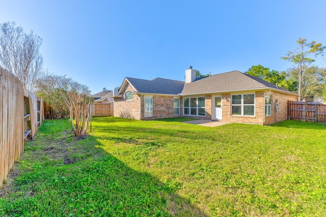 rear view of property with brick siding, a chimney, and a fenced backyard