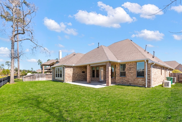 back of property featuring a patio, a fenced backyard, a yard, roof with shingles, and brick siding