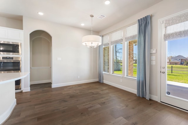 unfurnished dining area featuring dark wood-style floors, visible vents, recessed lighting, and arched walkways