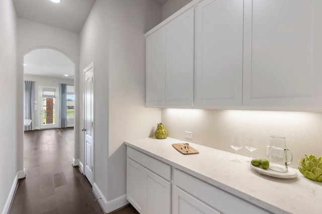 corridor featuring arched walkways, recessed lighting, dark wood finished floors, and baseboards