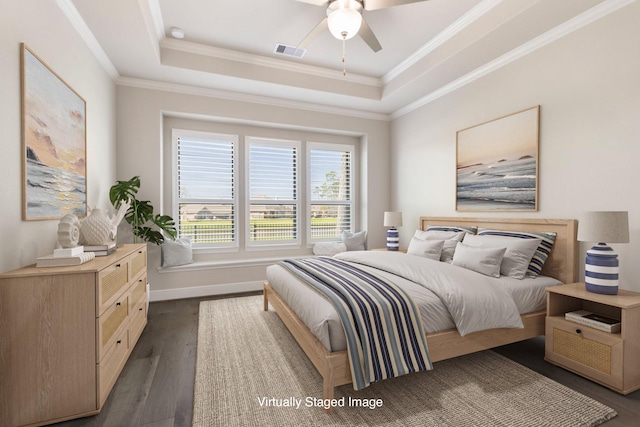 bedroom with visible vents, dark wood-type flooring, a tray ceiling, and ornamental molding