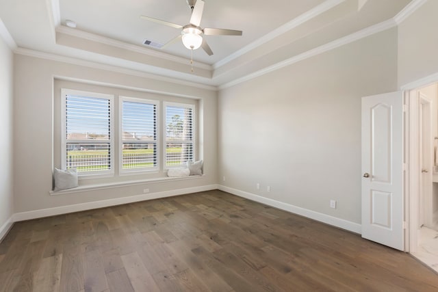 unfurnished room featuring visible vents, baseboards, dark wood finished floors, a tray ceiling, and ornamental molding