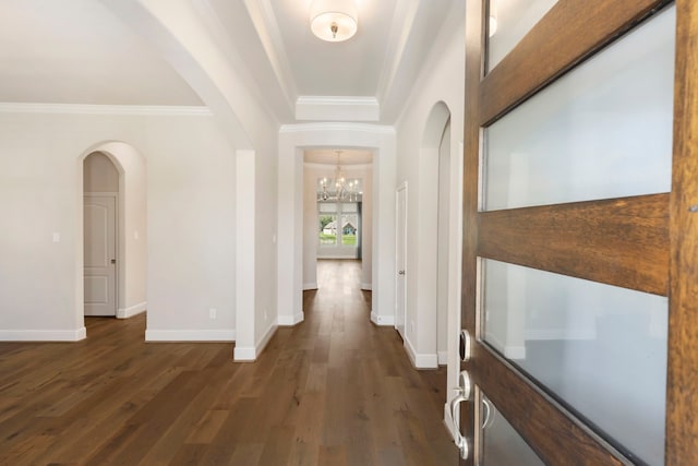 corridor with dark wood-style floors, crown molding, and baseboards