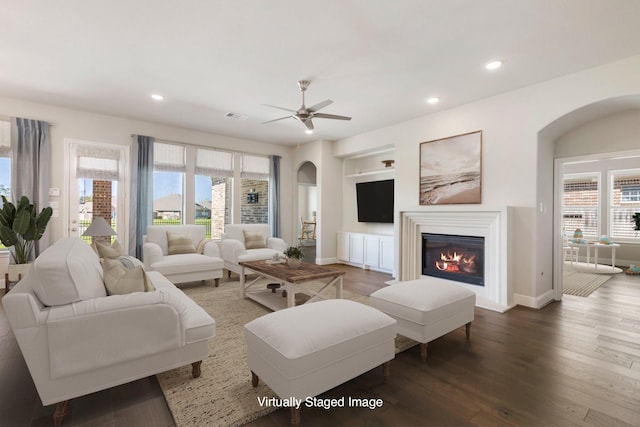 living room with a glass covered fireplace, recessed lighting, wood finished floors, and arched walkways