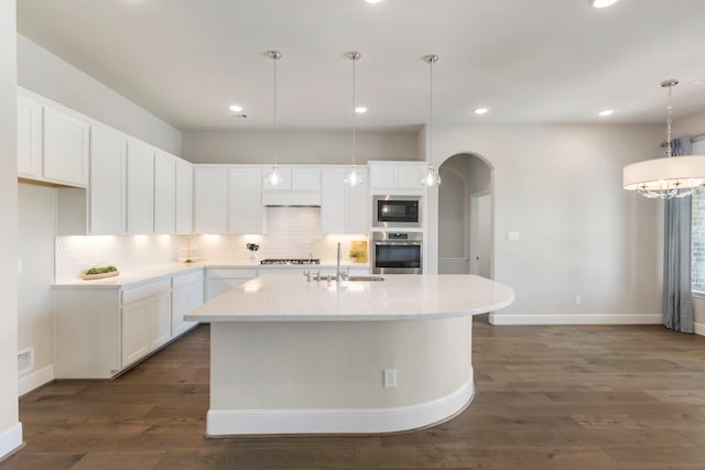 kitchen featuring gas cooktop, arched walkways, built in microwave, a sink, and oven