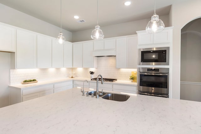 kitchen with decorative backsplash, white cabinetry, appliances with stainless steel finishes, and a sink