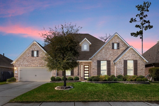 traditional-style home with brick siding, driveway, an attached garage, and a front lawn