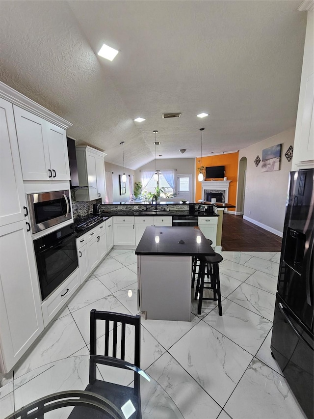 kitchen with a sink, visible vents, marble finish floor, black appliances, and dark countertops