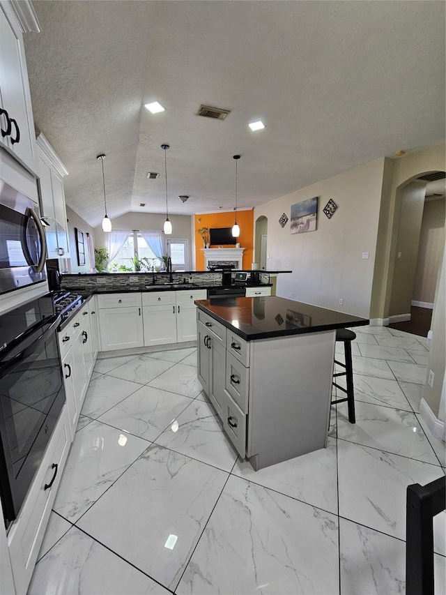 kitchen with arched walkways, marble finish floor, dark countertops, and a sink