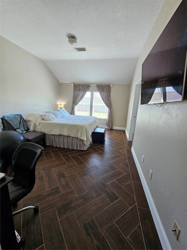 bedroom featuring vaulted ceiling, a textured ceiling, visible vents, and baseboards