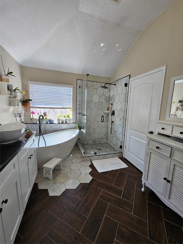 bathroom featuring lofted ceiling, a textured ceiling, vanity, a soaking tub, and a shower stall