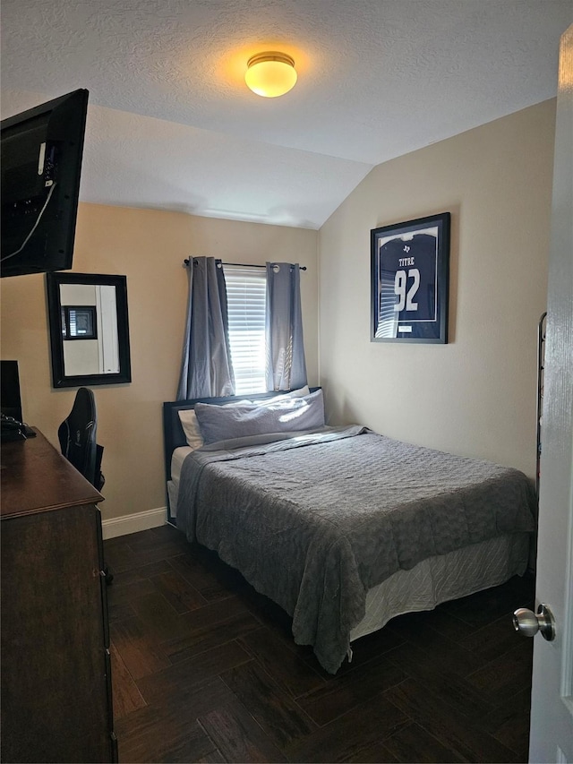 bedroom featuring lofted ceiling, baseboards, and a textured ceiling