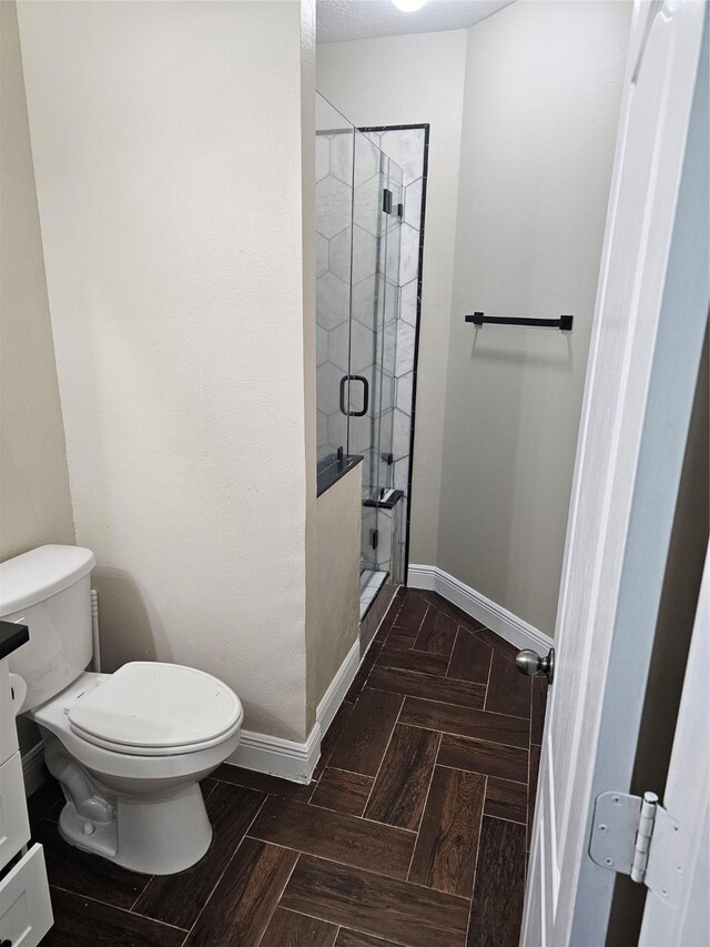 bathroom with toilet, a stall shower, and baseboards