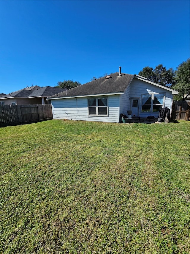 rear view of property featuring fence and a yard