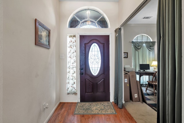 foyer entrance with baseboards, visible vents, and wood finished floors