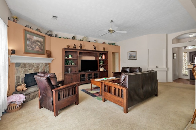 carpeted living room featuring a textured ceiling, ceiling fan, a fireplace, and visible vents