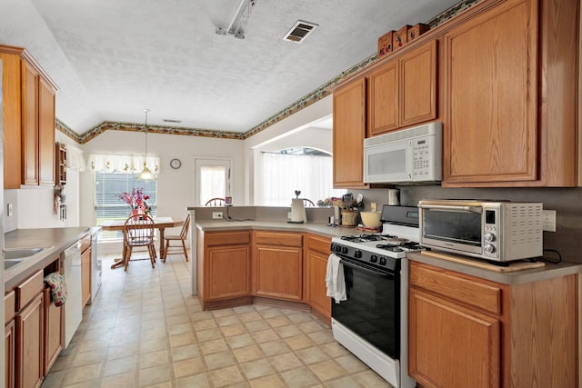 kitchen featuring a toaster, visible vents, a textured ceiling, white appliances, and a peninsula