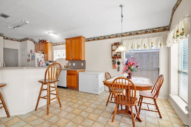 kitchen featuring tasteful backsplash, a wealth of natural light, white appliances, and visible vents