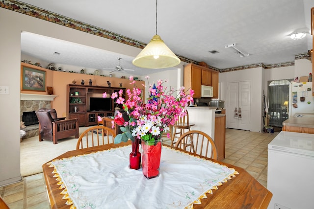 dining room featuring a ceiling fan, visible vents, a fireplace, and a textured ceiling