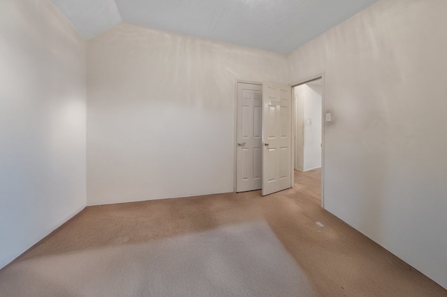 empty room with lofted ceiling and light colored carpet