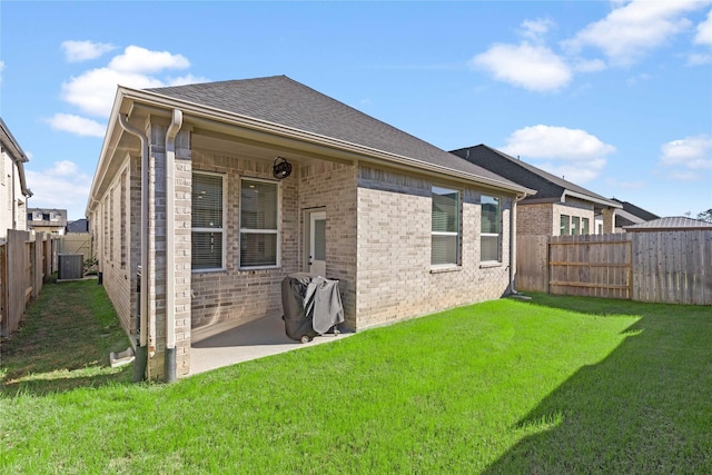 rear view of property with brick siding, a lawn, central AC unit, a patio area, and a fenced backyard