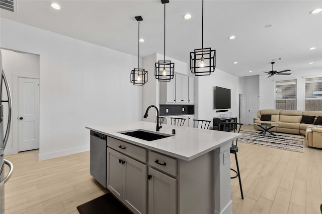 kitchen featuring dishwasher, visible vents, light wood finished floors, and a sink